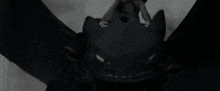 toothless from how to train your dragon is flying through the air with its wings outstretched .