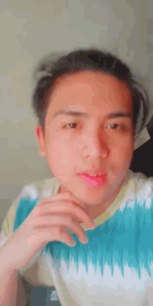 a young man wearing a tie dye shirt is making a funny face .