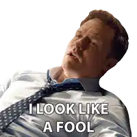 a man in a suit and tie is laying down and says i look like a fool