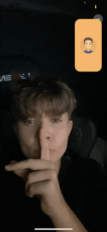 a young man holds his finger to his lips while talking on a video call