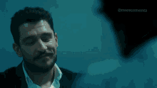 a man with curly hair and a beard is wearing a sweater and making a funny face .