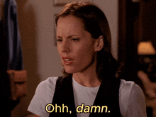 a woman wearing a white shirt and black vest says " ohh damn "