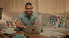 a man sits on a couch using a laptop