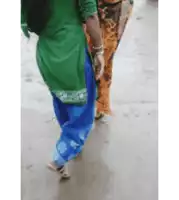 a woman in a green top and blue pants walks down a street