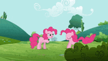 two pink ponies standing in a grassy field with trees in the background