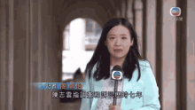 a woman in a blue jacket holds a microphone in front of a screen that says ' o ' on it