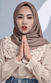 a woman wearing a hijab and a lace collar is praying