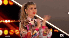 a woman is clapping her hands on a stage while wearing a colorful outfit .