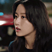 a close up of a woman 's face with long hair and a car in the background .