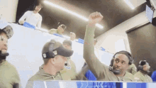 a man wearing a headset holds his fist up in the air in front of a group of people