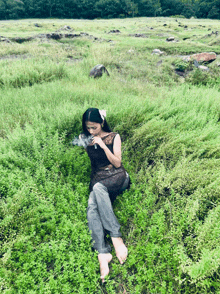 a woman laying in the grass with a flower in her hair smoking a cigarette