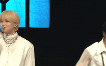 a man with blonde hair is wearing a white shirt and necklace