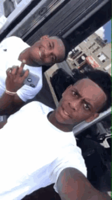 two young men are posing for a picture and one is holding a phone that says ' abercrombie & fitch ' on it