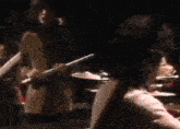 a woman in a red tank top is standing in front of a man playing a flute