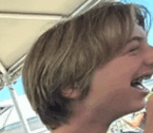 a close up of a man 's face with his mouth open and a umbrella in the background .