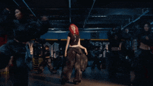 a woman with red hair is dancing in a dark room with a sign that says ' n ' on it