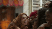 a group of women are hugging and laughing together .