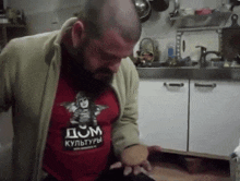 a man with a beard is wearing a red shirt that says dom cultures