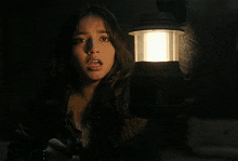 a woman holding a lantern in a dark room with her mouth open