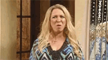 a woman with long blonde hair is making a funny face while standing in front of a mirror .