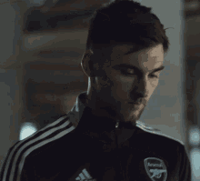 a man in a black adidas jacket looks at the camera