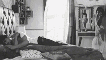 a black and white photo of two people laying on a bed in a bedroom .