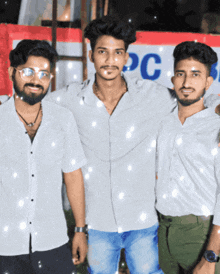 three young men pose for a picture in front of a pc sign