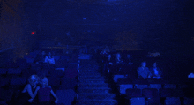 two women are sitting in a dark auditorium with a blue light shining on them