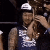 a man in a blue thunder jersey holds a trophy