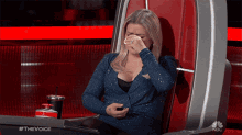 a woman is crying while sitting in a chair with #thevoice on the bottom