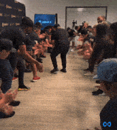a group of people are clapping their hands in front of a wall that says zone 8