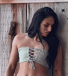 a woman in a lace up crop top is standing in front of a wooden wall
