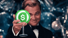 a man in a tuxedo holds a green coin with a dollar sign on it in front of his face
