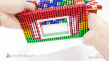 a person is holding a colorful toy that says magnetworld on it