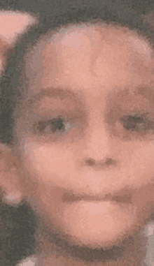 a close up of a child 's face with a pink bow on her head .