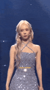 a woman in a blue dress is standing on a stage in front of a blue background .