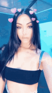 a woman in a black crop top with pink hearts in her hair