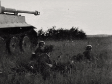 a black and white photo of soldiers and a tank in a field