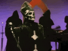 a skeleton priest is standing in front of a group of people holding a microphone .