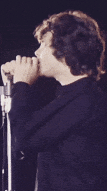 a person singing into a microphone with a black shirt on