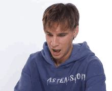 a young man wearing a blue hoodie that says asteasion