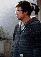 a young man wearing glasses and a blue striped hoodie with the word cooper on the pocket