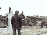 a man in a suit stands in front of a pile of junk with a sign that says ' ss ' on it