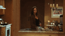 a woman is standing in a kitchen with a picture on the wall that says t.p.p.