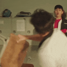 two men are fighting in a locker room and one of them is pointing at the other .