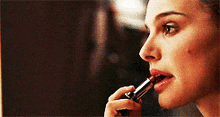 a woman is applying red lipstick to her lips in front of a mirror