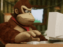 a stuffed donkey kong is typing on a white computer