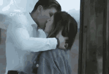 a man and a woman are kissing while standing next to a window .