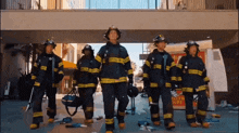 a group of firefighters are walking down a street in front of a hollywood tours sign