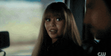 a woman is sitting in the back seat of a car with a cw logo in the corner